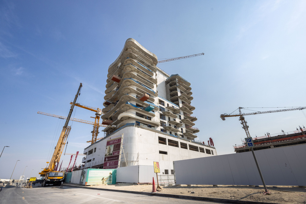 Beach Walk Iii By Imtiaz A large construction site with a modern building under development, cranes, and construction equipment visible.